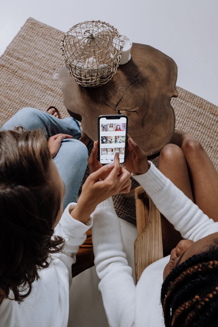 Crafting Captivating Headlines: Your awesome post title goes here Two people looking at social media on a smartphone at a wooden table.